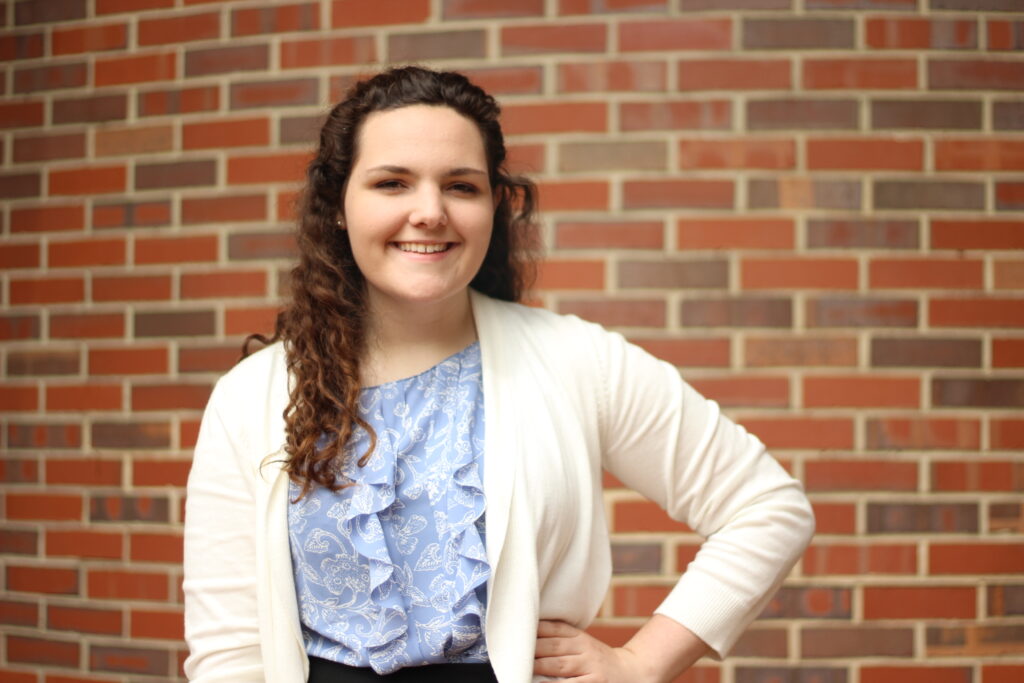 Anna Long stands before brick wall