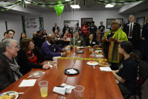 Woman stands at a full table and speaks to the crowd