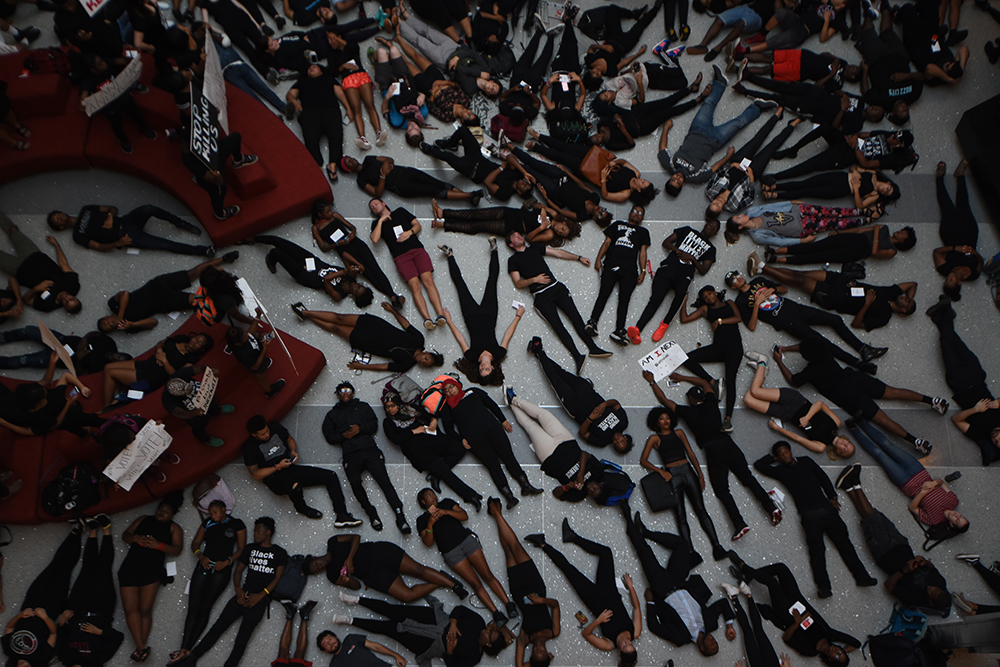 Students wearing all black lay on floor in Talley Student Union
