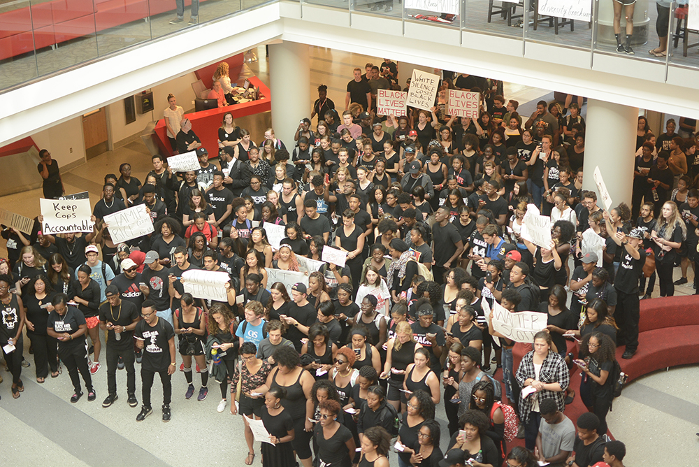 Students crowd in lobby of Talley Student Union holding signs