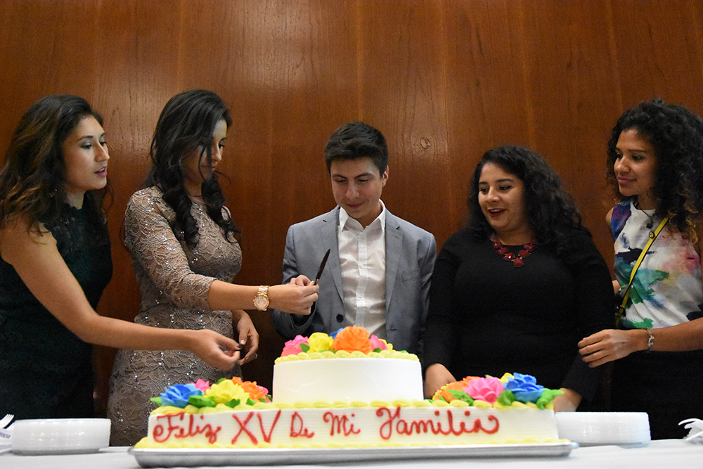 Five members of Mi Familia prepare to cut the cake at Mi Familia's 15th annual celebration