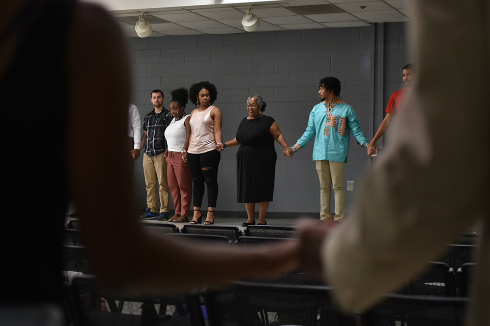 Two members of the audience join hands to celebrate the community spirit at the end of Harambee! 2018, presented by the African American Cultural Center (AACC). In the background, "Mama" Toni Thorpe, the retired program coordinator of the AACC, starts the Harambee! chant. Thursday, Sept. 6. (Swathi Karthik/Staff Photographer)